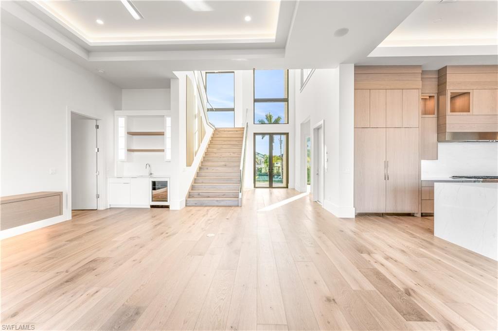 Unfurnished living room featuring a tray ceiling, light wood finished floors, and french doors