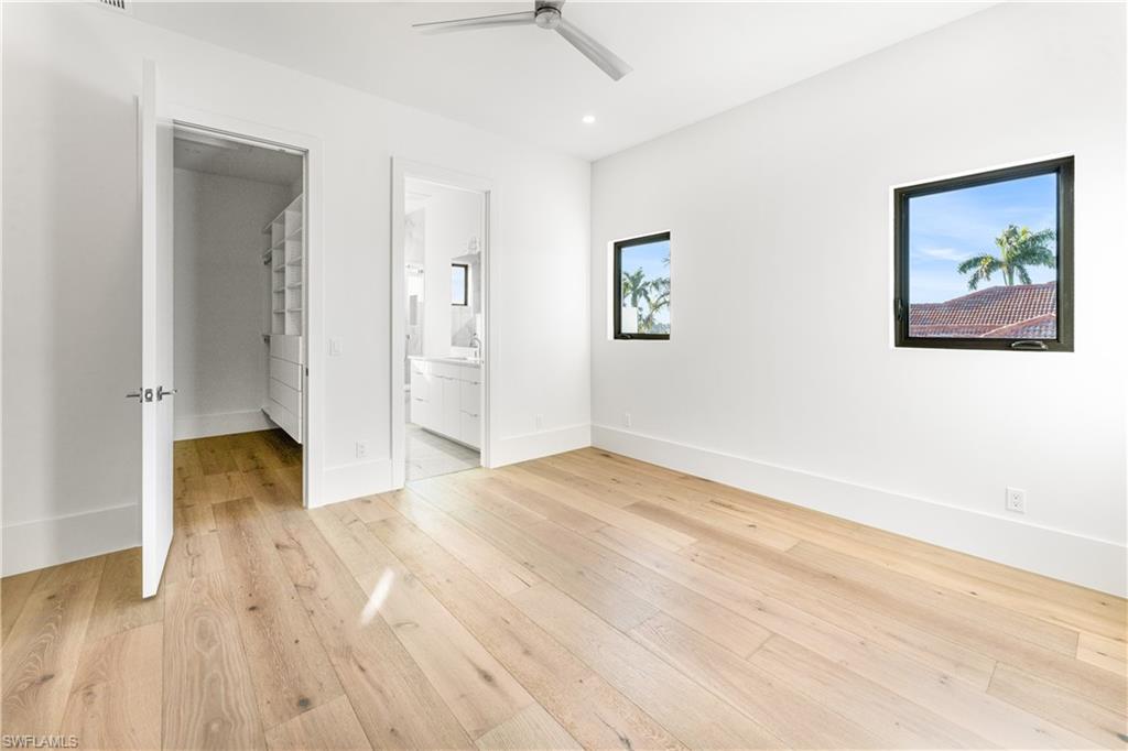 Unfurnished bedroom with light wood-style flooring, connected bathroom, and ceiling fan