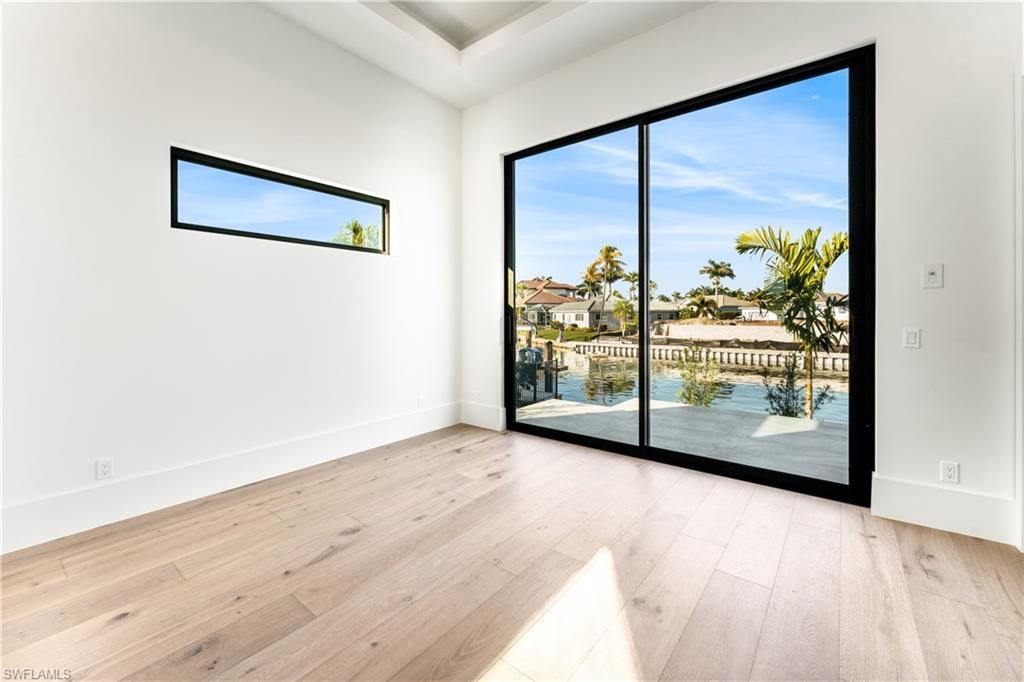 Unfurnished room with light wood-style floors, a residential view, and a water view