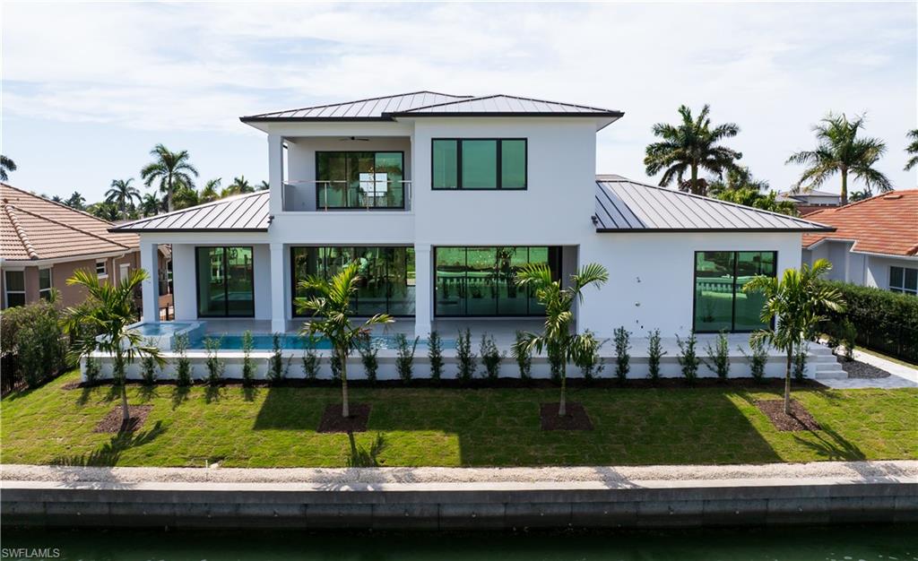 Modern home with a standing seam roof, a garage, decorative driveway, and a front yard