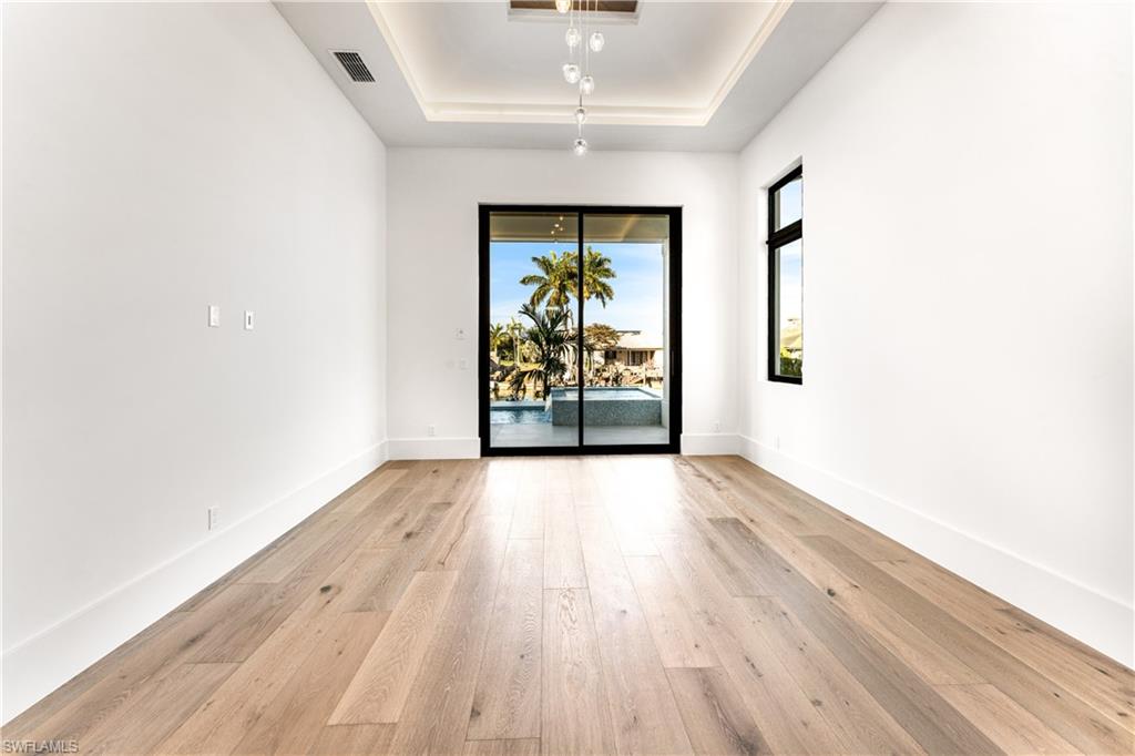 Empty room with a tray ceiling and light wood-type flooring