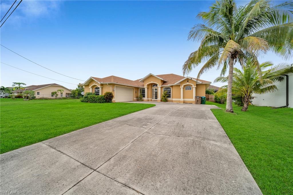 View of front of house with driveway, a front lawn, stucco siding, and an attached garage
