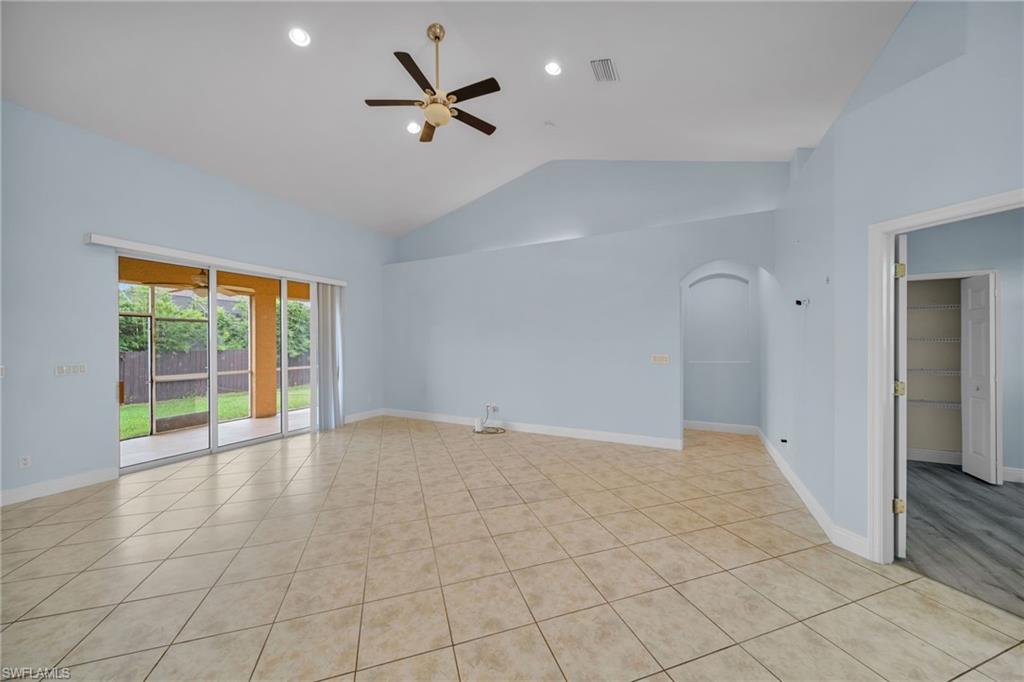 Unfurnished room featuring light tile patterned floors, arched walkways, a ceiling fan, and high vaulted ceiling