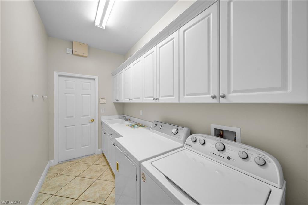 Laundry room featuring light tile patterned floors, cabinet space, and separate washer and dryer