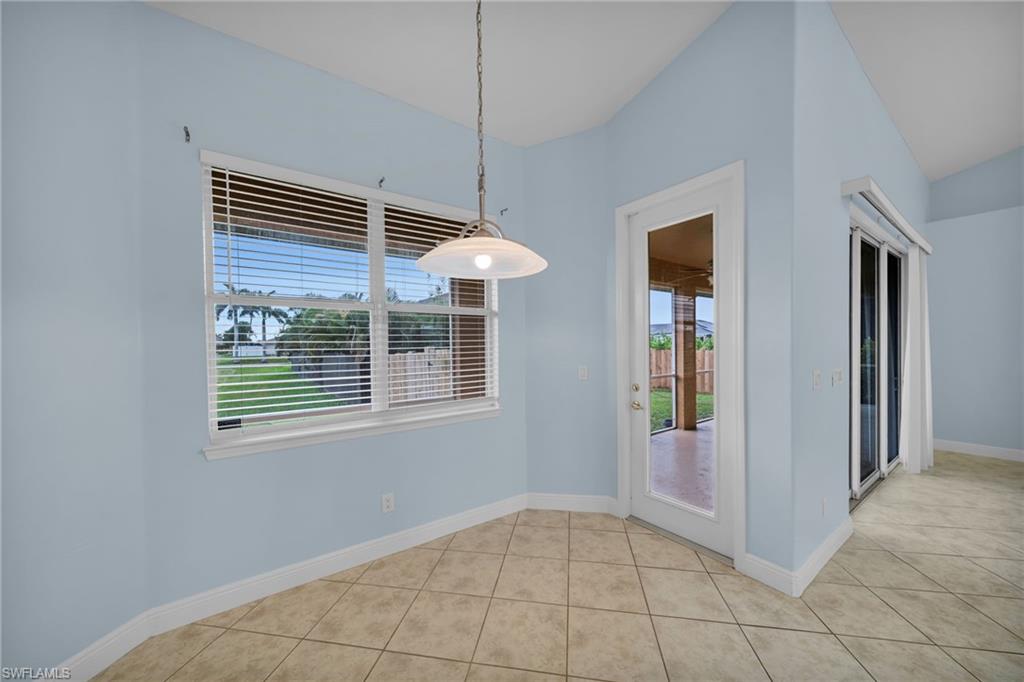 Unfurnished dining area featuring healthy amount of natural light, light tile patterned flooring, and vaulted ceiling