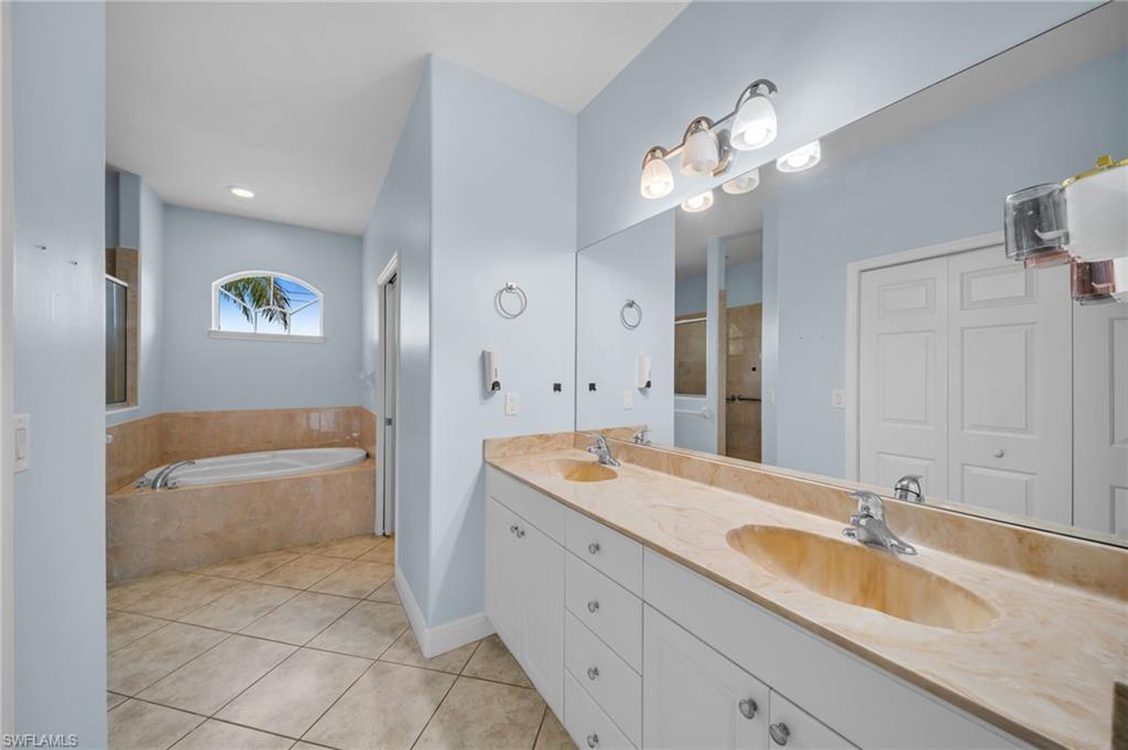 Bathroom featuring a garden tub, double vanity, light tile patterned flooring, and a shower stall