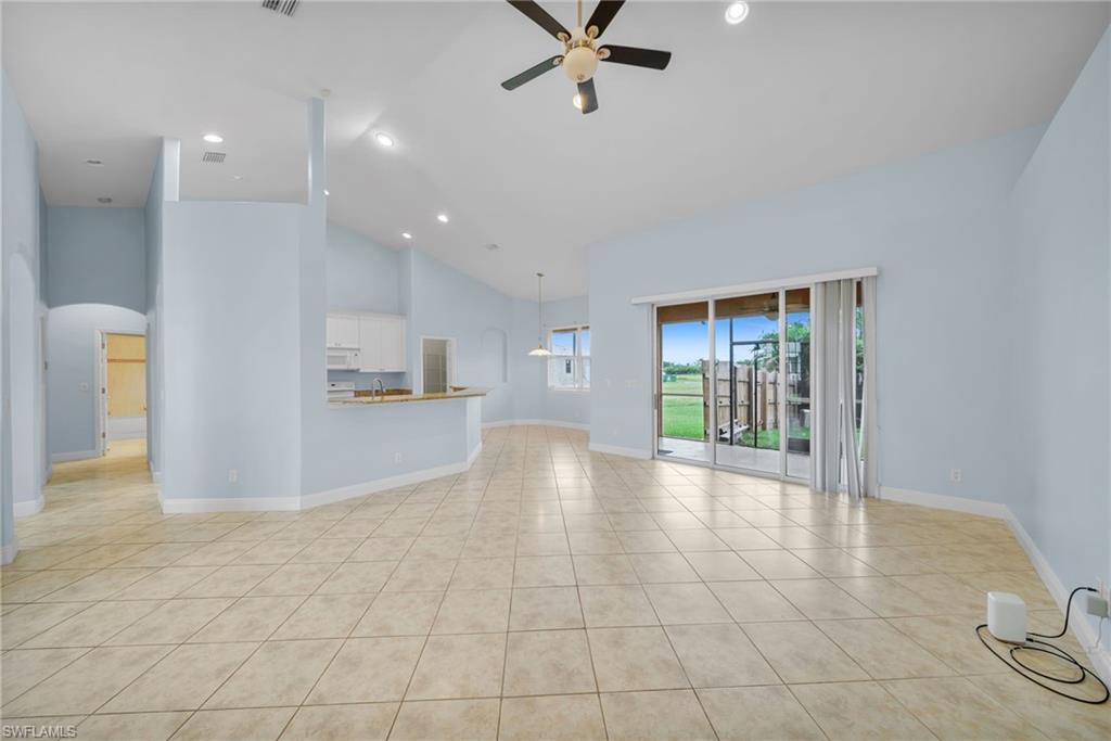 Unfurnished living room with high vaulted ceiling, arched walkways, light tile patterned flooring, a ceiling fan, and recessed lighting