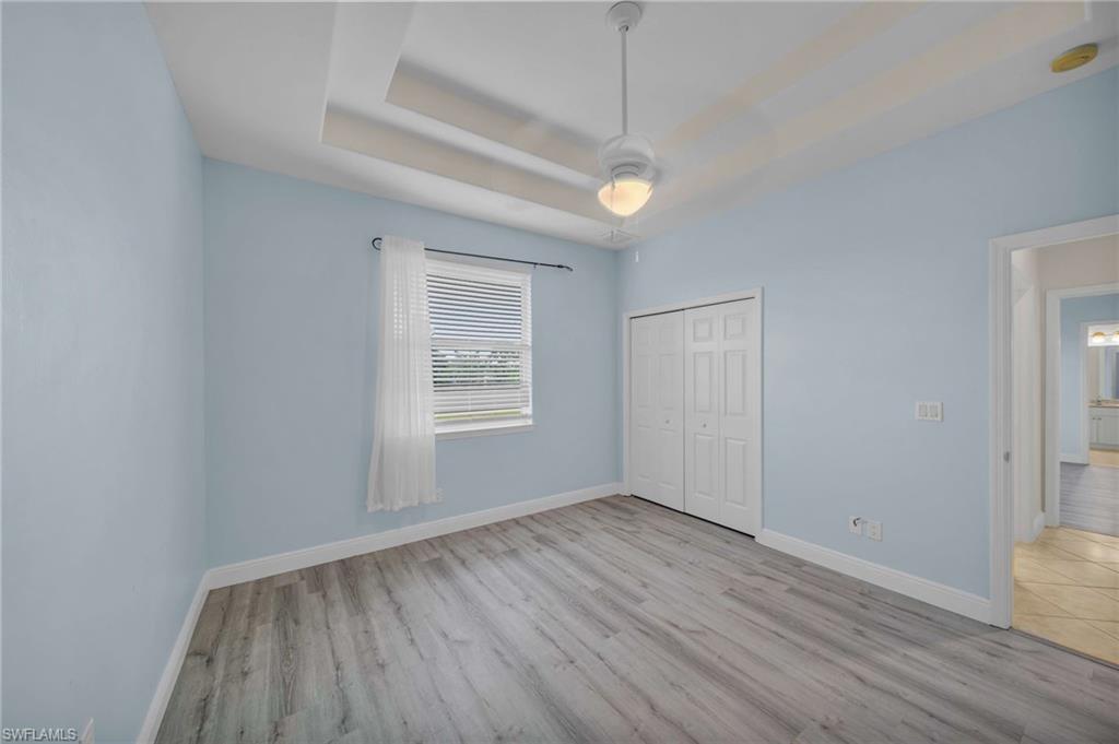 Unfurnished bedroom featuring a tray ceiling, light wood-type flooring, and a closet