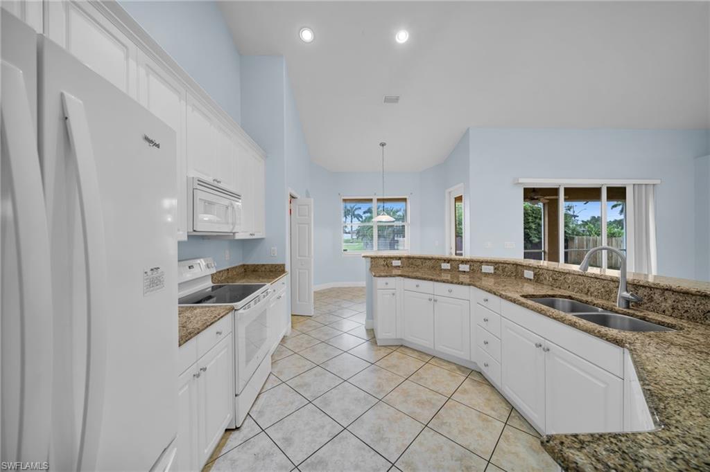 Kitchen with white appliances, white cabinets, recessed lighting, light tile patterned flooring, and hanging light fixtures