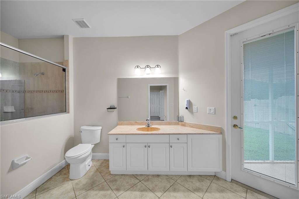 Full bath featuring vanity, a tile shower, and light tile patterned flooring