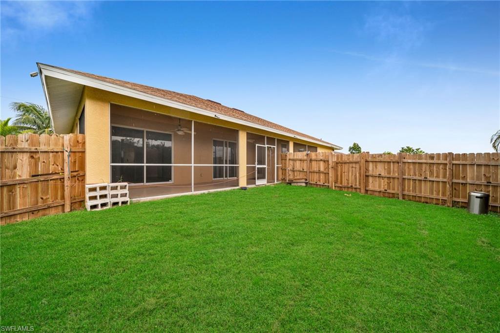 Back of property featuring a sunroom, a fenced backyard, ceiling fan, and stucco siding