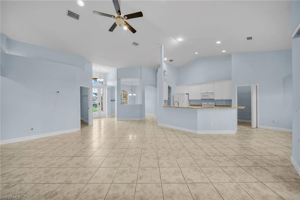 Unfurnished living room featuring high vaulted ceiling, light tile patterned floors, a ceiling fan, recessed lighting, and arched walkways