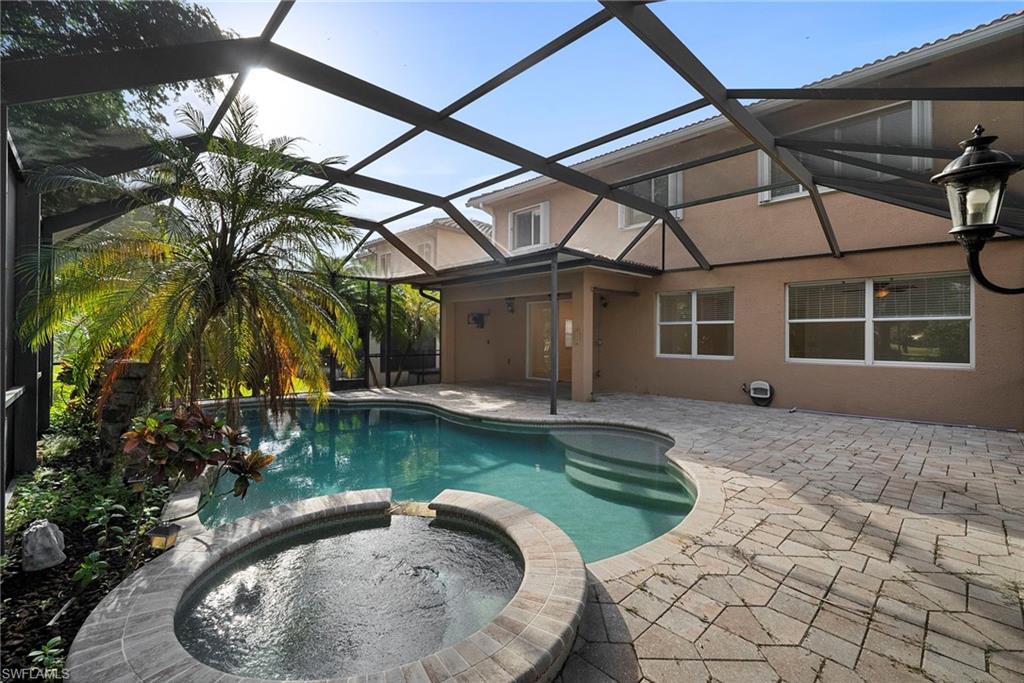 View of swimming pool with a sunroom, a pool with connected hot tub, a patio area, and a lanai