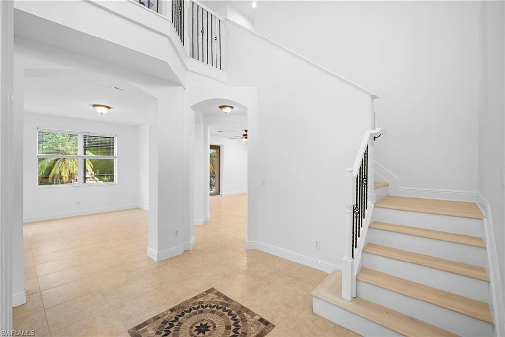 Stairway with arched walkways, a high ceiling, a ceiling fan, and tile patterned flooring