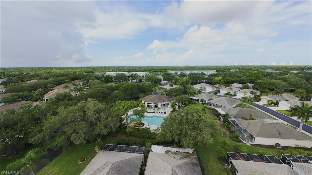 Aerial perspective showcasing a community pool and clubhouse, surrounded by mature trees