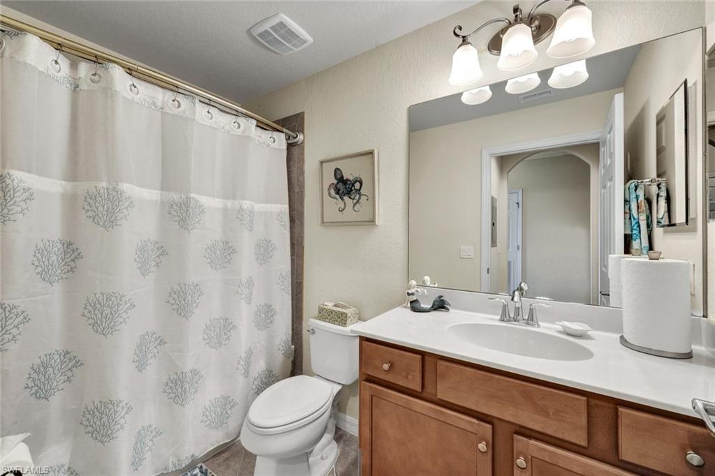 Bathroom featuring vanity, a textured wall, a shower with shower curtain, and light tile patterned floors