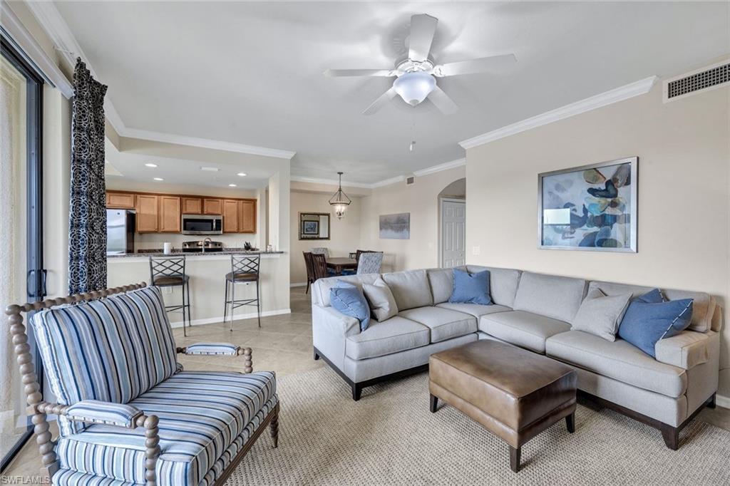 Living room with crown molding, arched walkways, recessed lighting, a ceiling fan, and light tile patterned floors