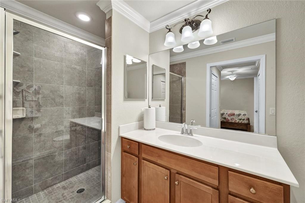 Full bathroom with ensuite bath, vanity, a stall shower, and ornamental molding