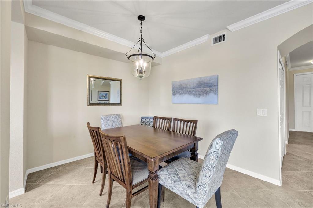 Dining room with crown molding, arched walkways, and light tile patterned floors