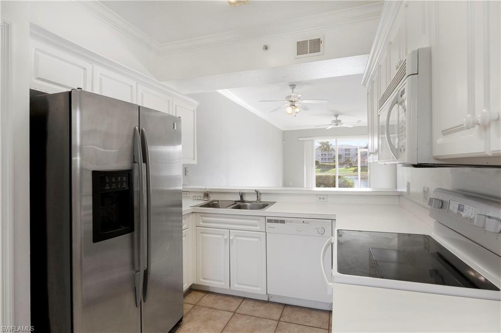 Kitchen with white appliances, crown molding, white cabinets, light tile patterned flooring, and light countertops