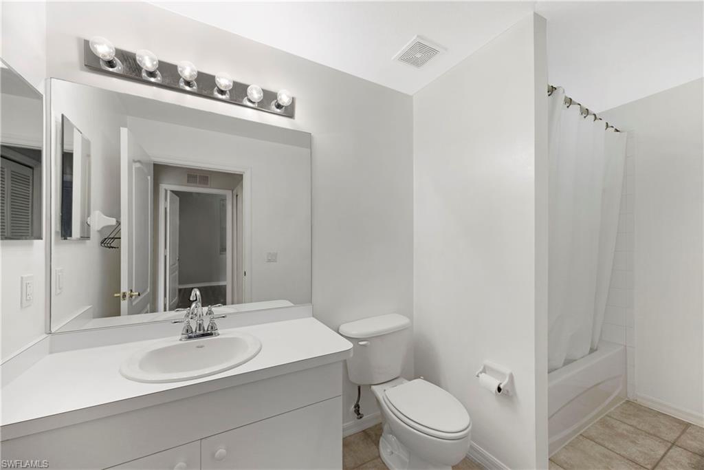 Bathroom featuring shower / bathtub combination with curtain, vanity, and light tile patterned floors