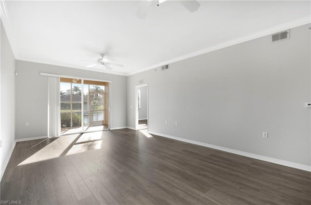 Unfurnished room featuring crown molding, dark wood-style floors, a water view, and ceiling fan