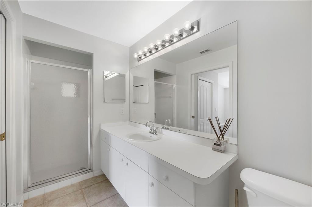Full bath featuring a stall shower, light tile patterned floors, and vanity