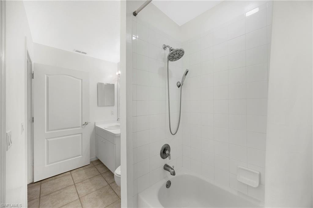Bathroom with washtub / shower combination, light tile patterned floors, and vanity