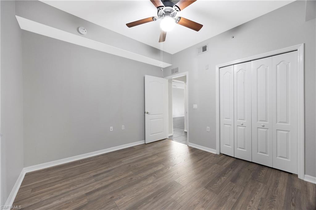 Unfurnished bedroom featuring dark wood-type flooring, a ceiling fan, and a closet