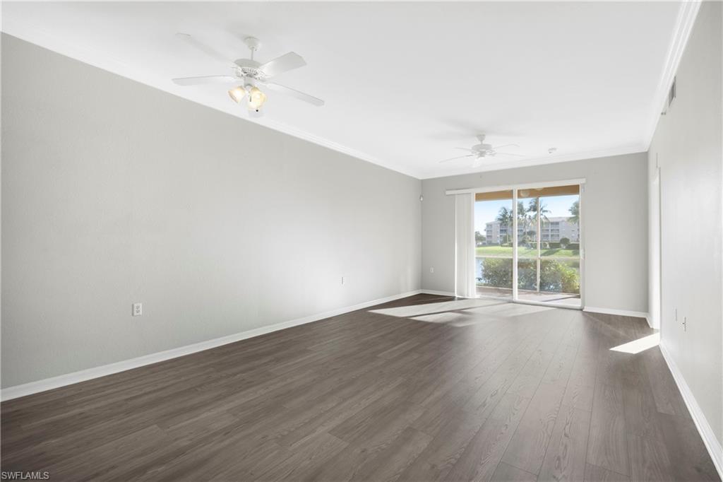 Spare room featuring dark wood finished floors, ornamental molding, a ceiling fan, and a water view
