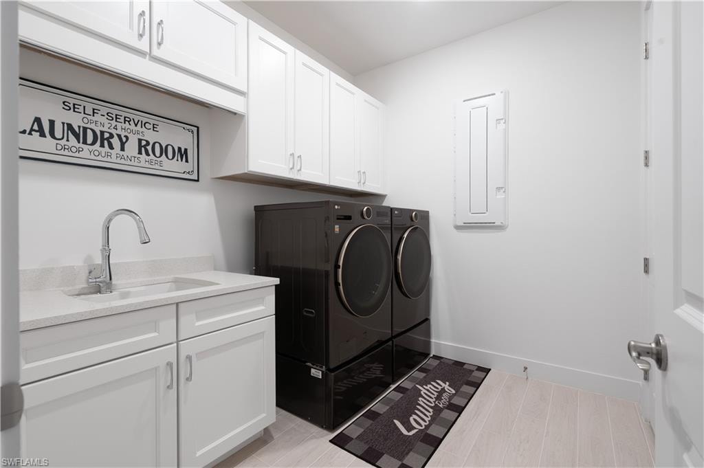 Laundry room with cabinet space, washer and dryer, electric panel, and light wood-type flooring