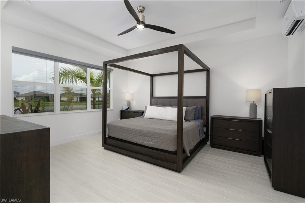 Bedroom featuring a wall mounted air conditioner, light wood finished floors, and a ceiling fan