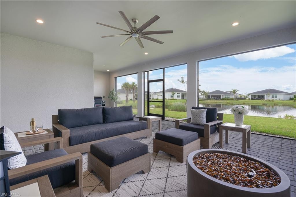Sunroom / solarium featuring recessed lighting, a water view, a textured wall, and a residential view