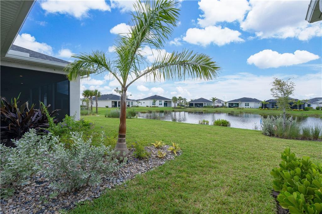 View of grassy yard with a water view, a residential view, and a sunroom