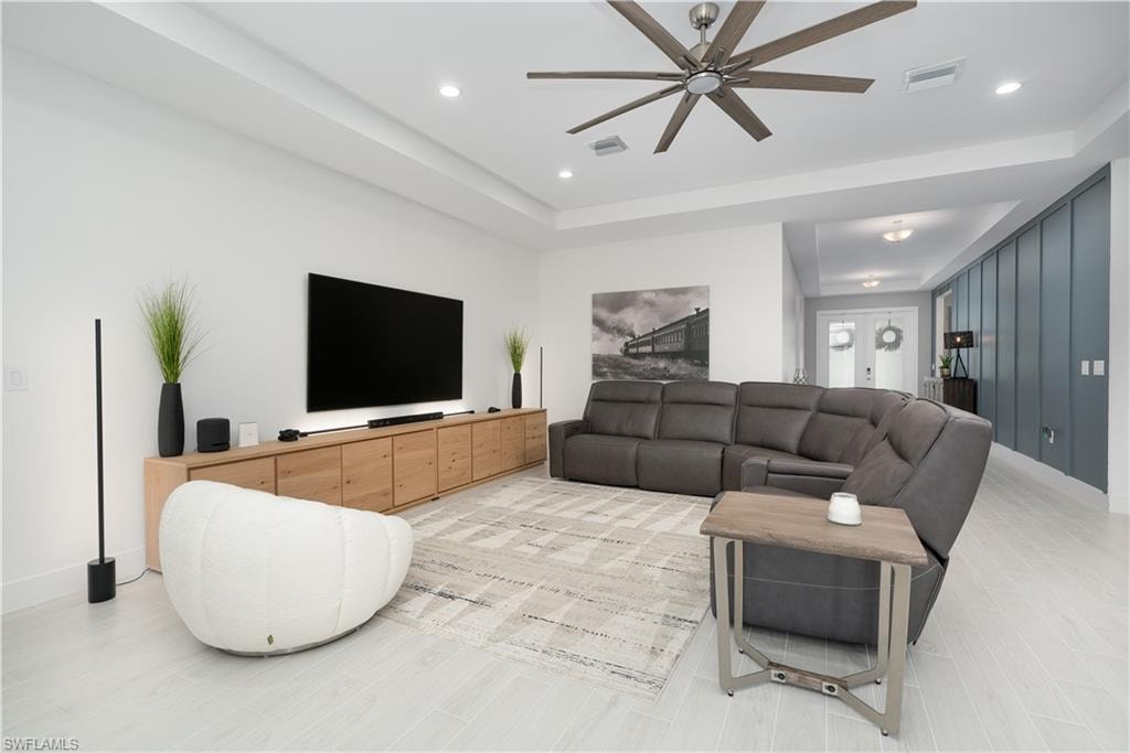 Living area with a tray ceiling, a ceiling fan, and recessed lighting