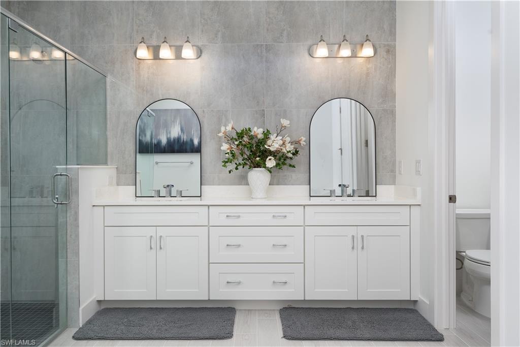 Bathroom featuring a stall shower, double vanity, and wood finish floors