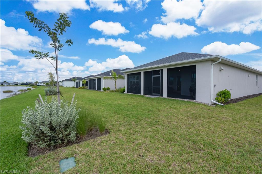 Rear view of property with a yard, a sunroom, and stucco siding
