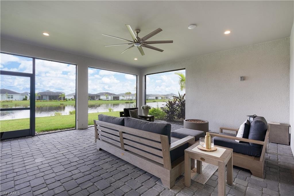 Sunroom featuring a residential view, a textured wall, a water view, and recessed lighting