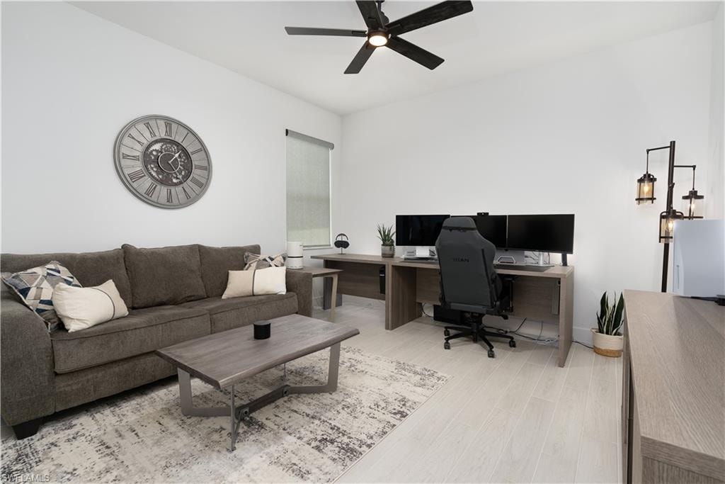 Home office with light wood-style flooring and ceiling fan