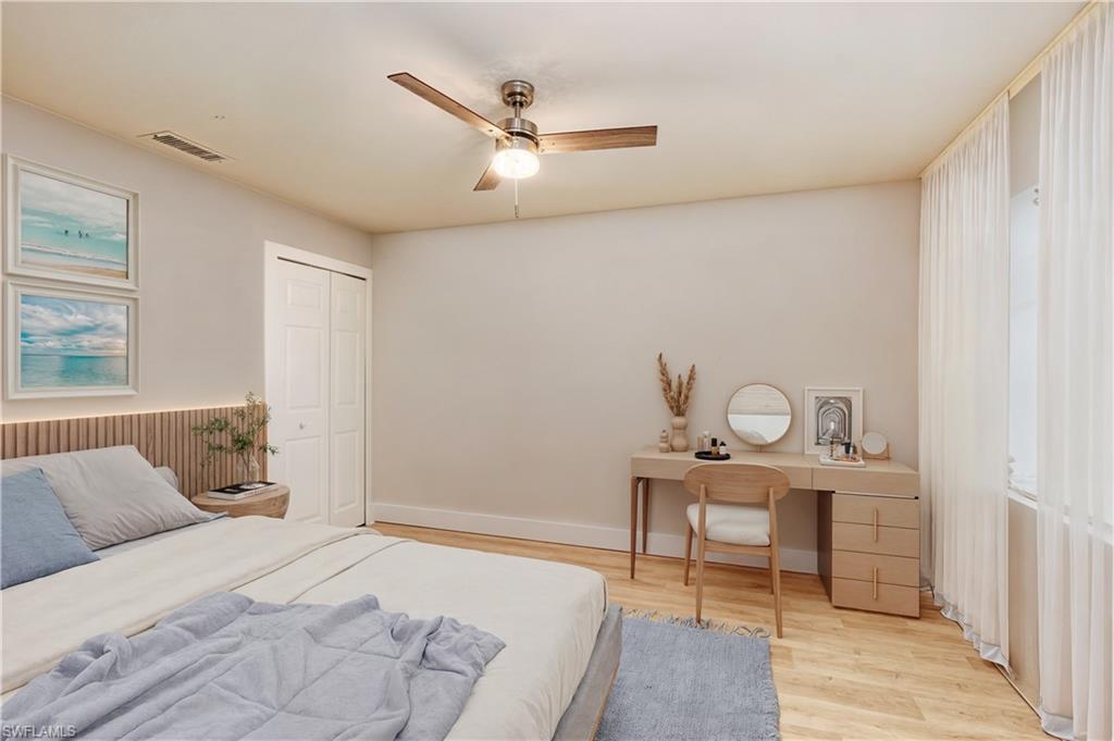 Bedroom with light wood-style flooring, a closet, a ceiling fan, and an office area