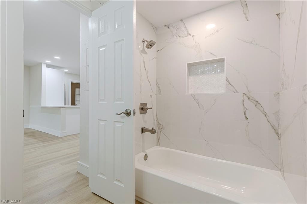 Bathroom featuring washtub / shower combination, light wood-style floors, and recessed lighting