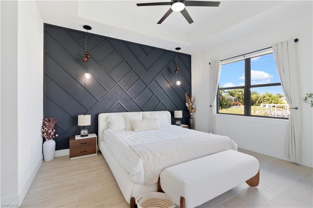 Bedroom featuring an accent wall, wood finished floors, and a tray ceiling