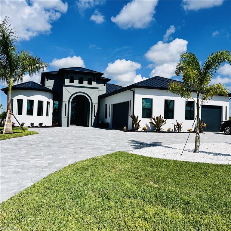 View of front facade with a standing seam roof, a metal roof, an attached garage, and circular driveway