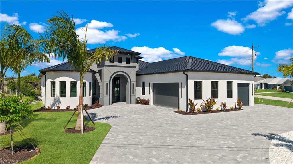 View of front facade with a metal roof, a standing seam roof, a garage, decorative driveway, and a front yard
