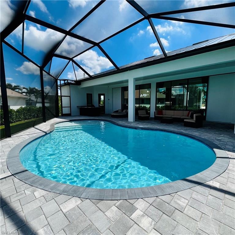 Swimming pool with an outdoor living space, a sunroom, glass enclosure, and a patio area