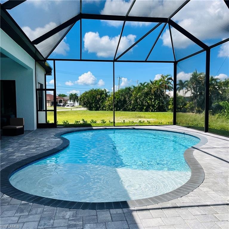 Swimming pool with a sunroom, a lanai, a yard, and a patio