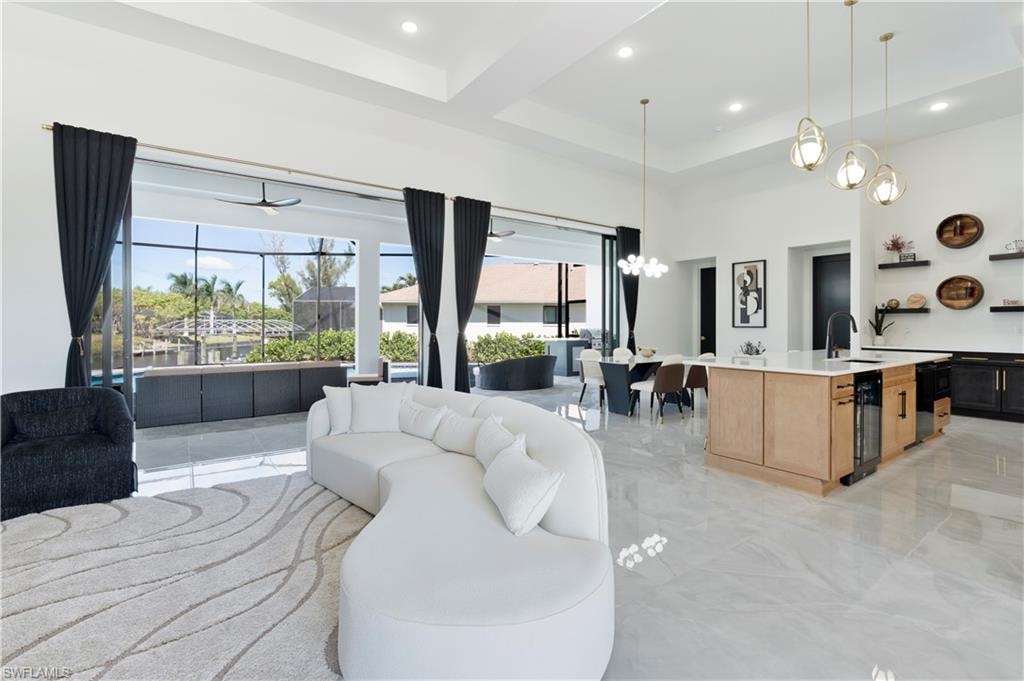 Living area with light marble finish flooring, a towering ceiling, beamed ceiling, wine cooler, and coffered ceiling