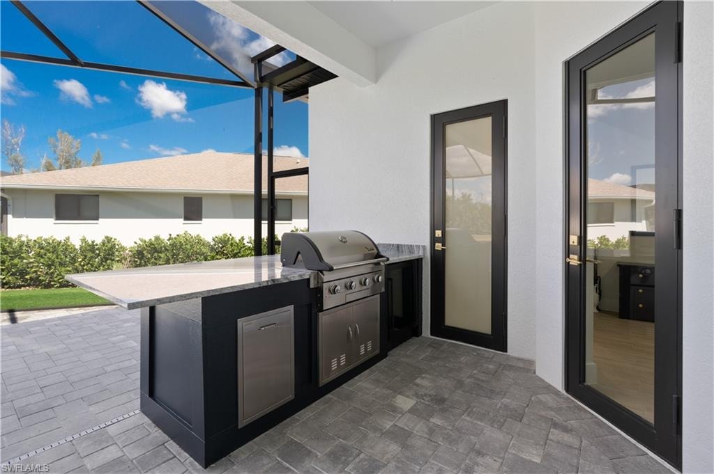 View of patio featuring area for grilling, a lanai, and a sunroom