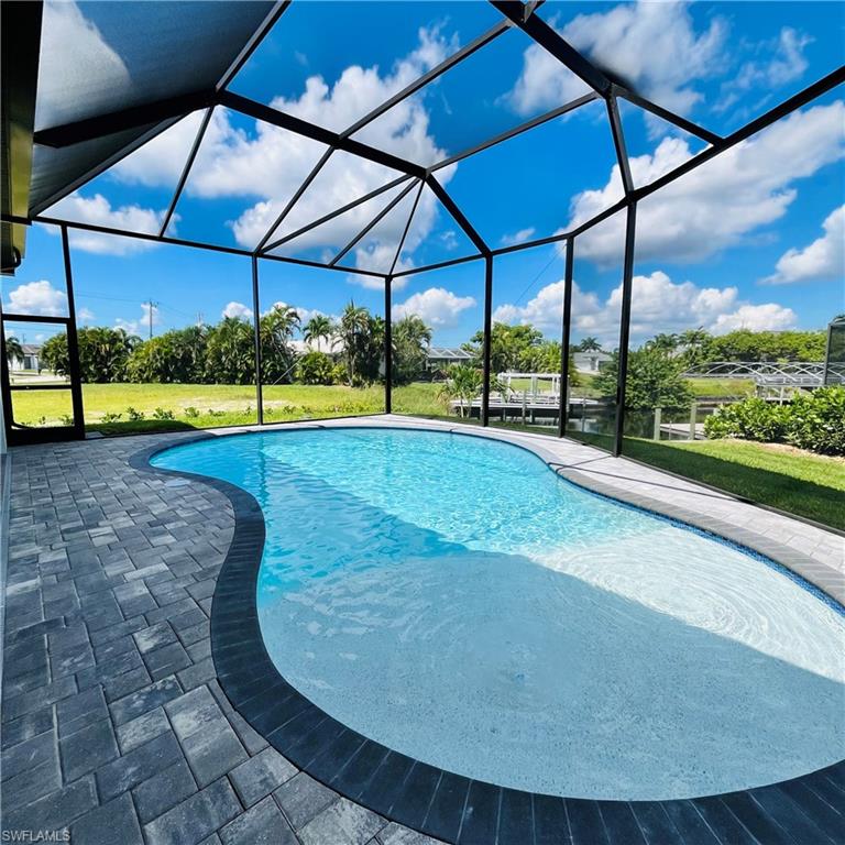 Swimming pool with glass enclosure, a sunroom, a lawn, and a patio