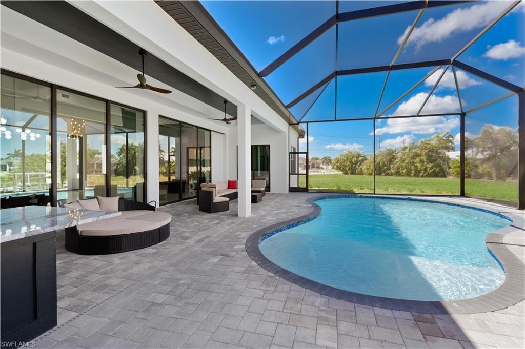 Outdoor pool featuring a ceiling fan, a sunroom, a patio area, outdoor lounge area, and a lanai